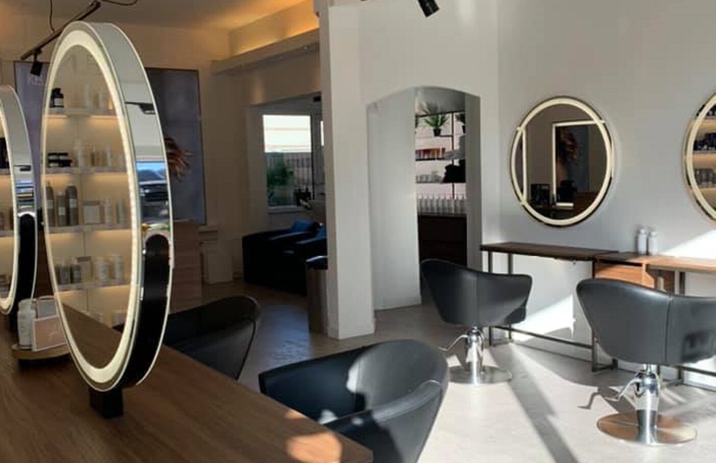 Salon met verlichte ronde spiegels en productwand